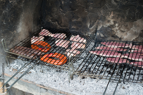 Barbecue with two cooking grills full of pork and chicken meat, chorizo and blackpudding photo