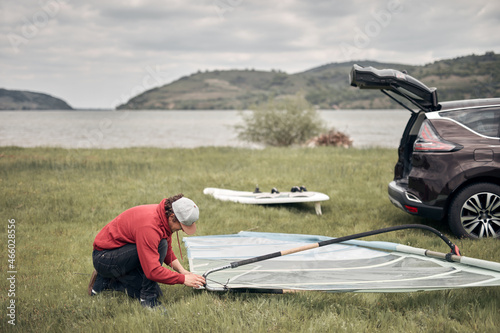 Tableau sur toile Windsurfer and camper packing and unpacking from a car in nature.
