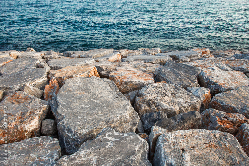 Boulders are large, artificial reinforcement, piled on seashore in front of water. Boulders are large, artificial reinforcement, piled on seashore in front of water.