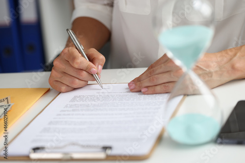 Fototapeta Naklejka Na Ścianę i Meble -  Female hand puts signature in contract at workplace