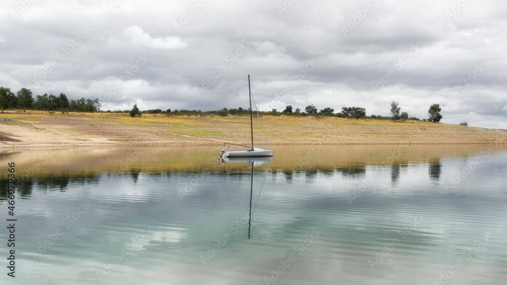 Embarcacion de recreo relejandose en las aguas tranquilas del lago en un dia con nubes