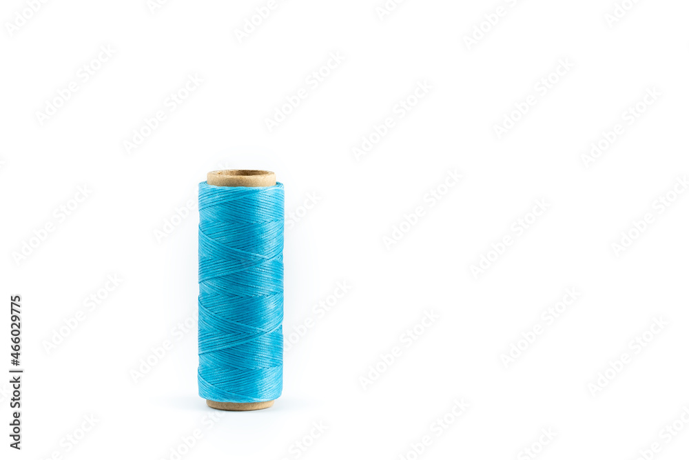 A coil of cyan thread. Spool of colored threads on a white background. Waxed sewing thread for leather crafts. A coil of cyan thread. Spool of colored threads on a white background. Waxed sewing thread for leather crafts.