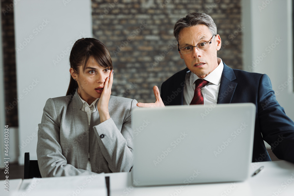 Mid adult manager and his younger colleague looking at something on a computer in the office Mid adult manager and his younger colleague looking at something on a computer in the office