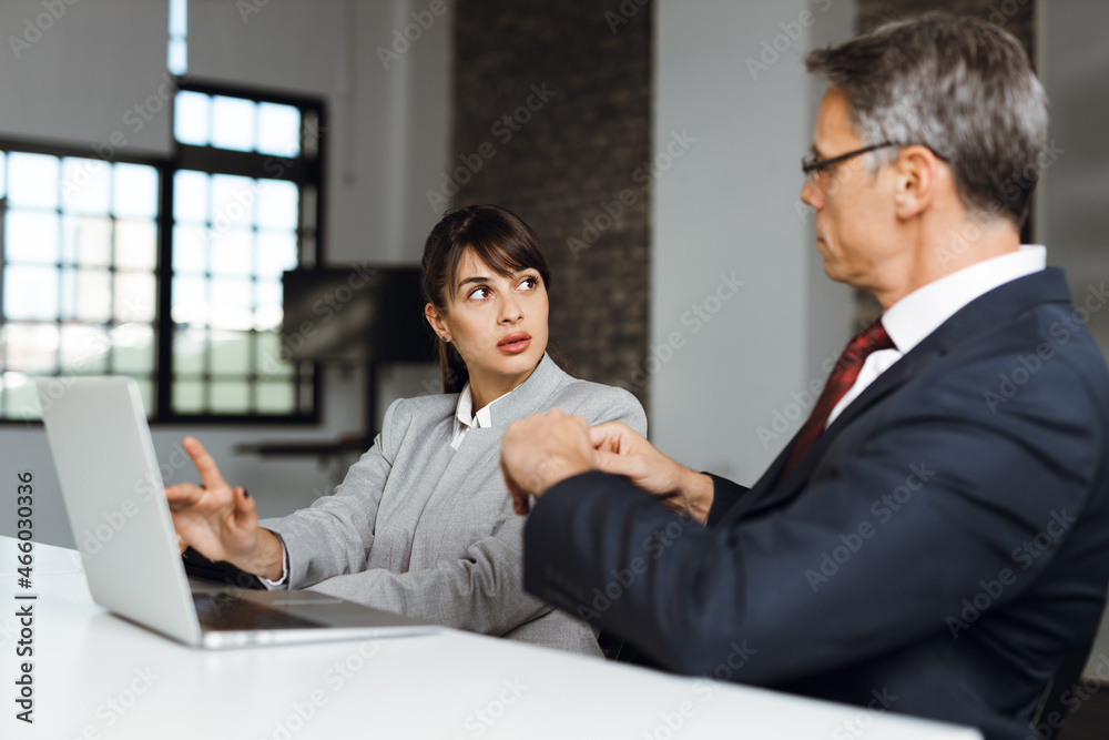 Business colleagues cooperating while working on laptop in the office