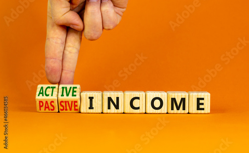 Passive or active income symbol. Businessman turns wooden cubes and changes words passive income to active income. Beautiful orange background, copy space. Business, passive or active income concept. photo