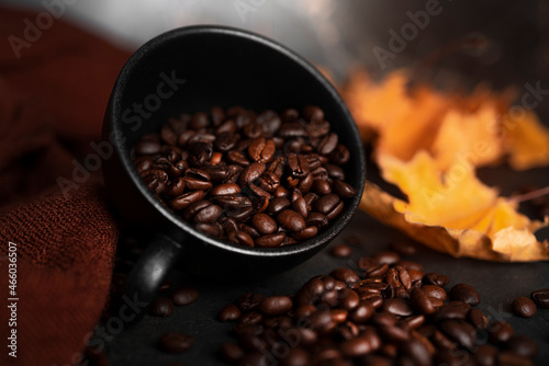 Coffee beans in a cup on a dark background. Autumn, coffee composition. Maple leaves, brown scarf. Flat lay.
