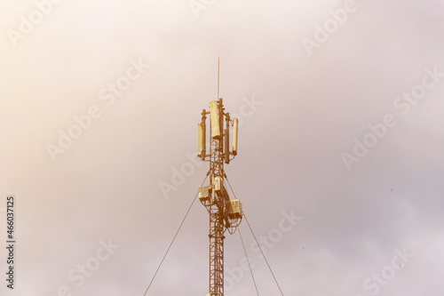 Mobile operator tower against the background of the sky in the rays of the setting sun.
