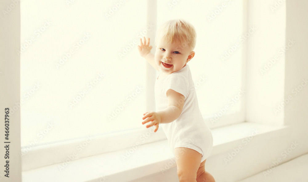 little baby touching window in white room at home little baby touching window in white room at home