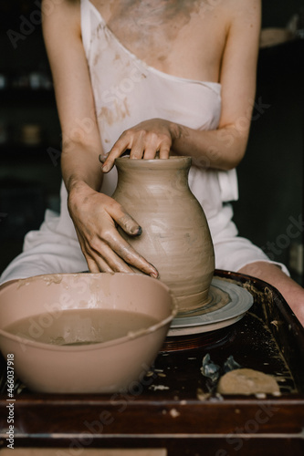 young girl in a white shirt makes a pitcher of clay on a potter's wheel. Pottery workshop of a creative woman. Concept - hobby clay modeling