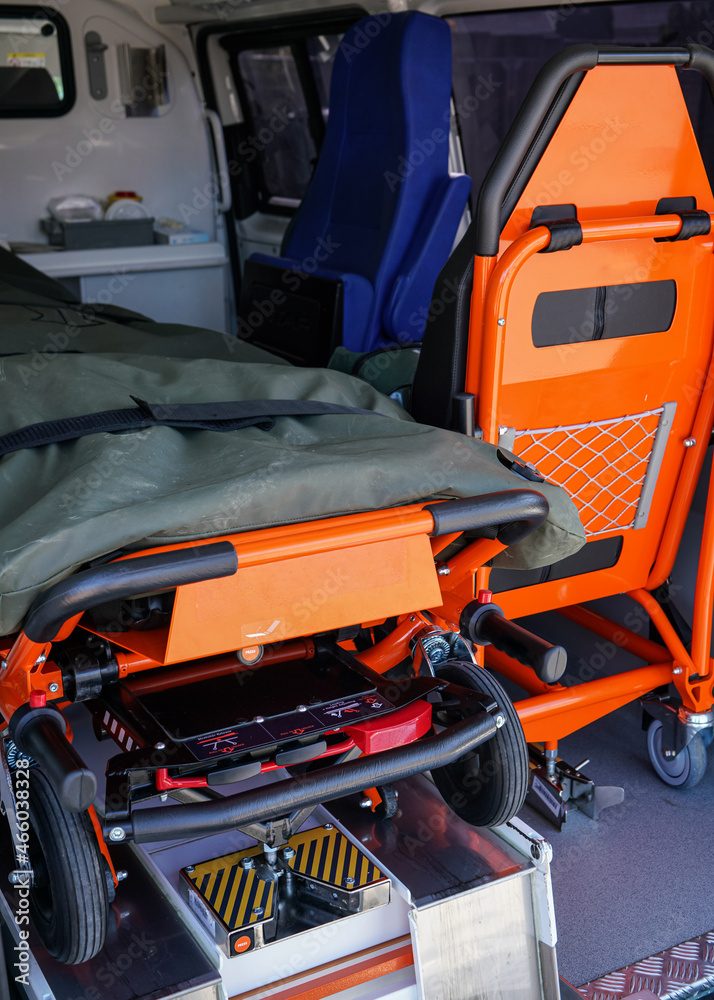 Back of ambulance vehicle, bright orange carrying stretcher and patient chair visible