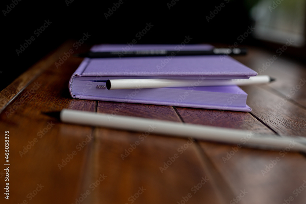 purple creative diary for writing with pencils and a capillary pen lies on a wooden table. concept is planning and writing in a notebook.
