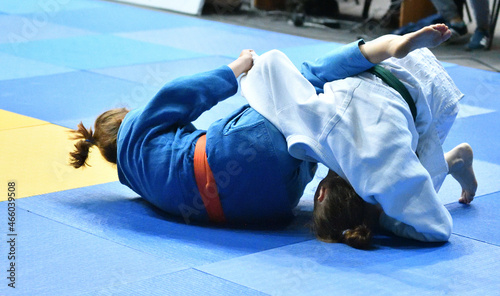 Two Girls judoka in kimono compete on the tatami 