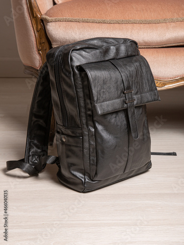 Black backpack bag with straps with zippers. bag for things, accessories and textbooks is in interior of apartment.