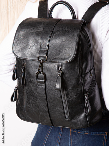 Black backpack bag with straps with zippers. bag for things, accessories and textbooks is in interior of apartment.