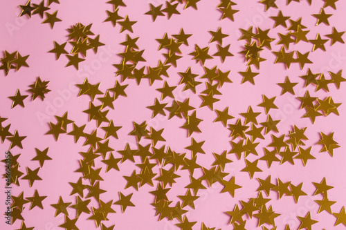 Bright colorful confetti stars sparkles on a pink background, the theme of a holiday and a birthday.