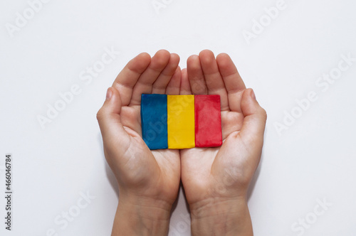 flag of Romania made of plasticine in the hands of a child on a white background
