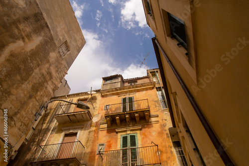 City landscape of Sicilian Ragusa Ibla old town. Sandstone houses, balconies, nobody on the street. Bright sunny view from below photo good for touristic booklets, travel company website, posters etc