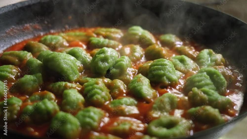 Spinach gnocchi with tomato sauce cooking in a hot pan