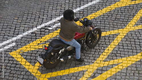 Motociclista montado na mota parado dentro do losango do rectângulo de proibição de paragem - contraste de cores e cruzamento de linhas photo