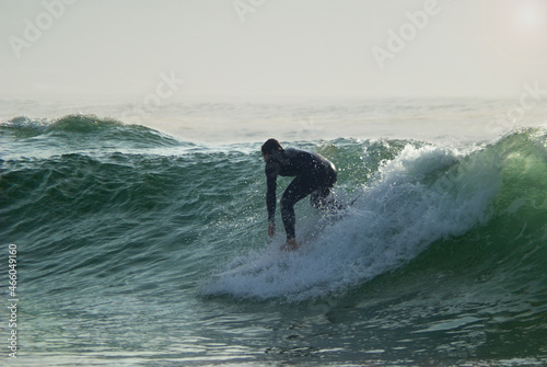 Surfista em cima da prancha a surfar uma onda, posição abaixado, prancha curta