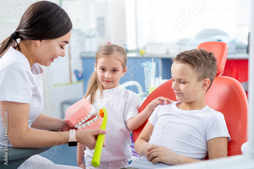 pediatric dentist shows young children how to brush their teeth properly. Children - a boy and a girl in doctor s office. concept is health of children s teeth.