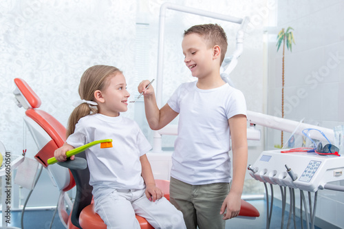 little boy and a girl in dentist's office. Children play dentist, hold a toothbrush and an apple in their hands. concept is health of children's teeth.