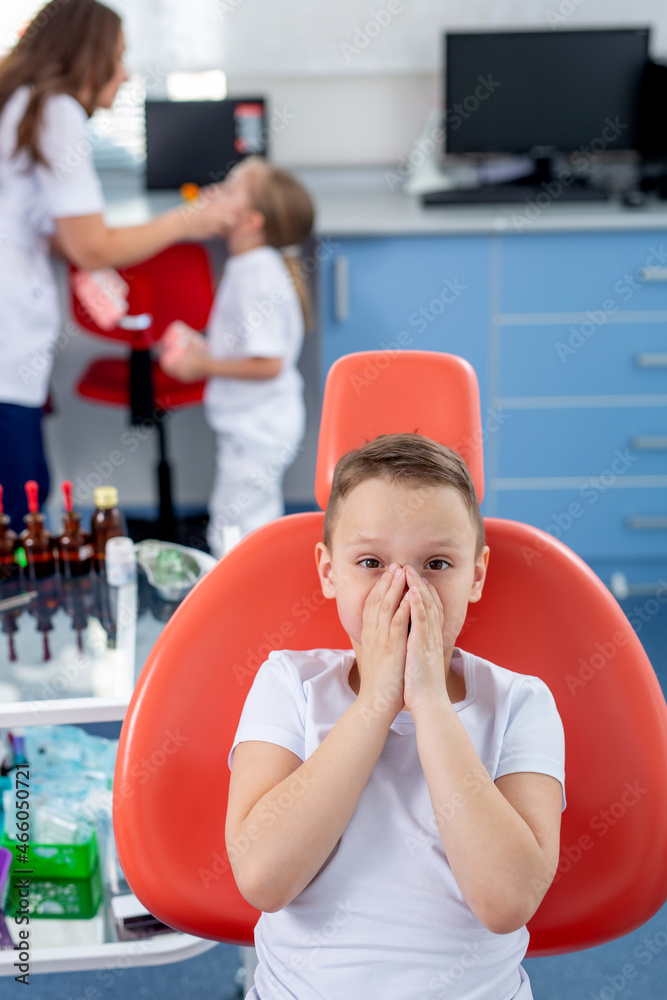 little boy child is afraid to show his teeth to the dentist. boy is at the reception of a pediatrician at clinic. Concept - checking caries in children