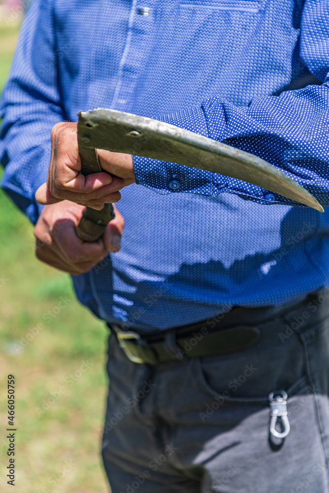 A man holding a scythe in a mountain village.