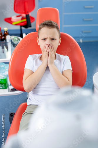 little boy child is afraid to show his teeth to the dentist. boy is at the reception of a pediatrician at clinic. Concept - checking caries in children