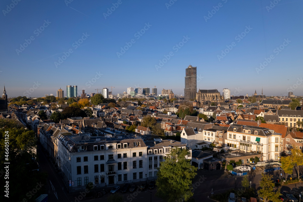 Urban housing in The Netherlands with aerial view of residential homes in Dutch city centre of Utrecht with cathedral in scaffolding towering over the historic town at sunrise