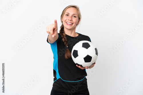 Young football player woman isolated on white background surprised and pointing front © luismolinero