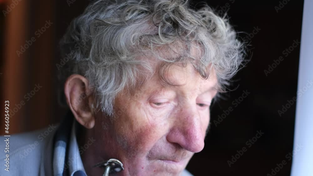 An elderly man shaves his face in front of a mirror. The pensioner