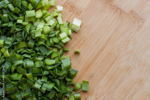 Finely chopped fresh green onions on a wooden cutting board with blurred edges with space for text photo