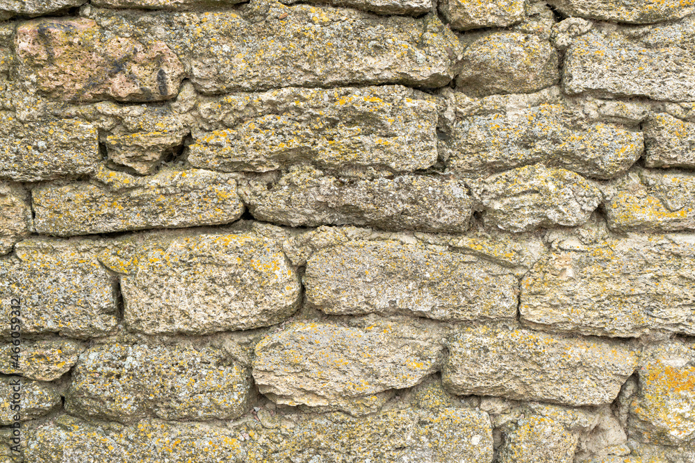 The fortress wall is made of natural stone. Ancient limestone stone. Creative vintage background. Ukraine. Belgorod - Dnestrovsky. The fortress wall is made of natural stone. Ancient limestone stone. Creative vintage background. Ukraine. Belgorod - Dnestrovsky.