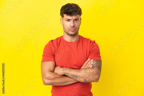 Young caucasian handsome man isolated on yellow background feeling upset