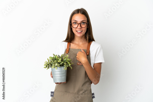 Gardener girl holding a plant over isolated white background with surprise facial expression