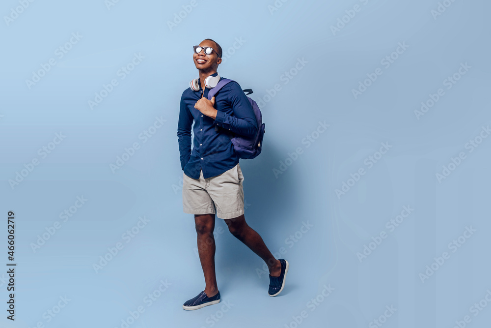 tourist black african man with backpack, headphones and sunglasses traveling with copy space on studio. tourist black african man with backpack, headphones and sunglasses traveling with copy space on studio.