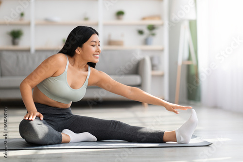 Fototapeta Naklejka Na Ścianę i Meble -  Sporty Young Beautiful Asian Woman Training At Home, Stretching In Living Room