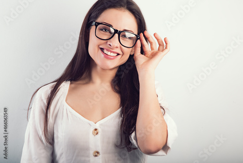 Beautiful natural smiling woman in modern glasses looking happy on blue background. Closeup