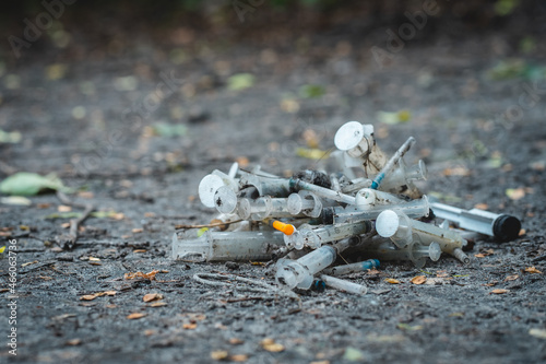 bunch of used dirty syringe leaved after drug injection lying on ground outdoor photo