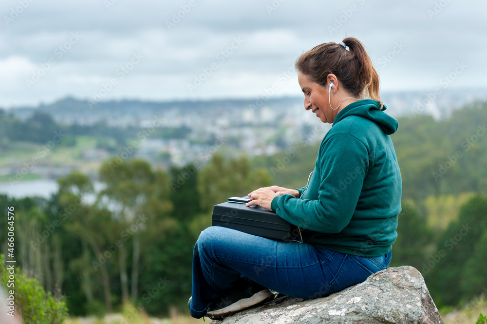 woman with cell phone and notebook laptop chatting on top of a mountain very relaxed contemplating the landscape woman with cell phone and notebook laptop chatting on top of a mountain very relaxed contemplating the landscape