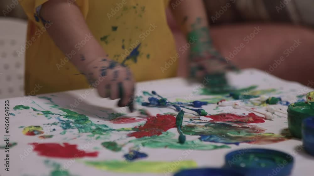 Artistic concept: child painting with hands on paper with water colours