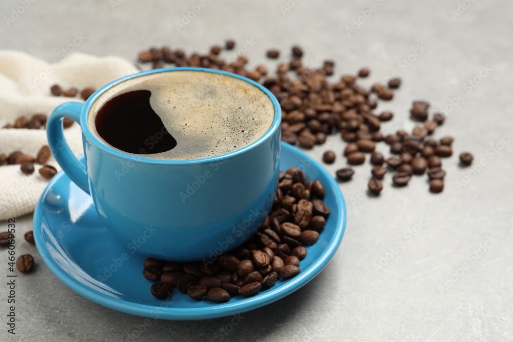 Cup of aromatic coffee and beans on light grey table Cup of aromatic coffee and beans on light grey table