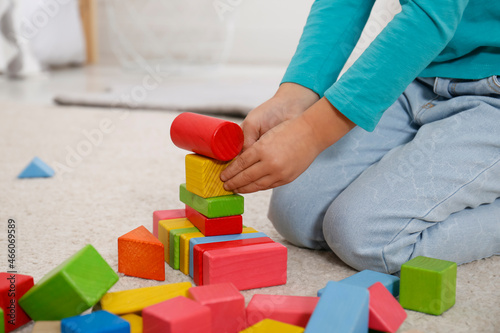 Cute little girl playing with colorful building blocks at home, closeup