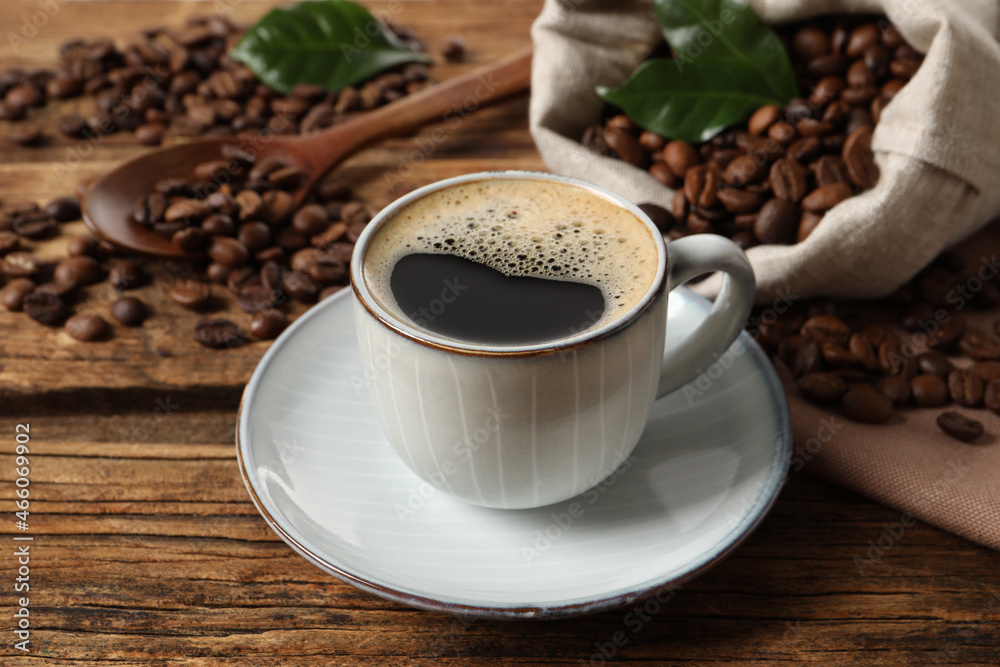 Cup of aromatic hot coffee and beans on wooden table Cup of aromatic hot coffee and beans on wooden table