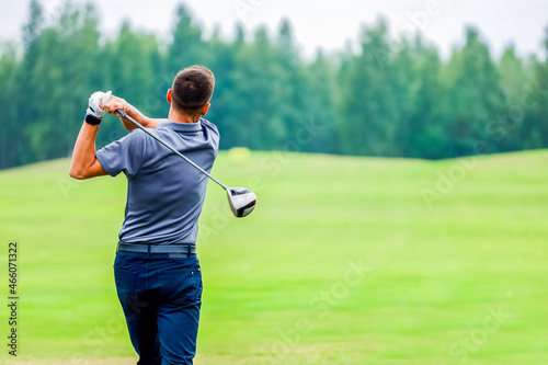 View from the back, a man playing golf on a forest background. High quality photo