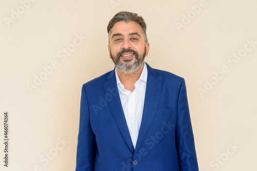 Portrait of bearded Indian businessman wearing suit against plain background