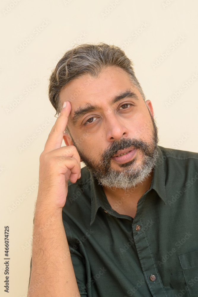 Portrait of bearded Indian businessman against plain background Portrait of bearded Indian businessman against plain background