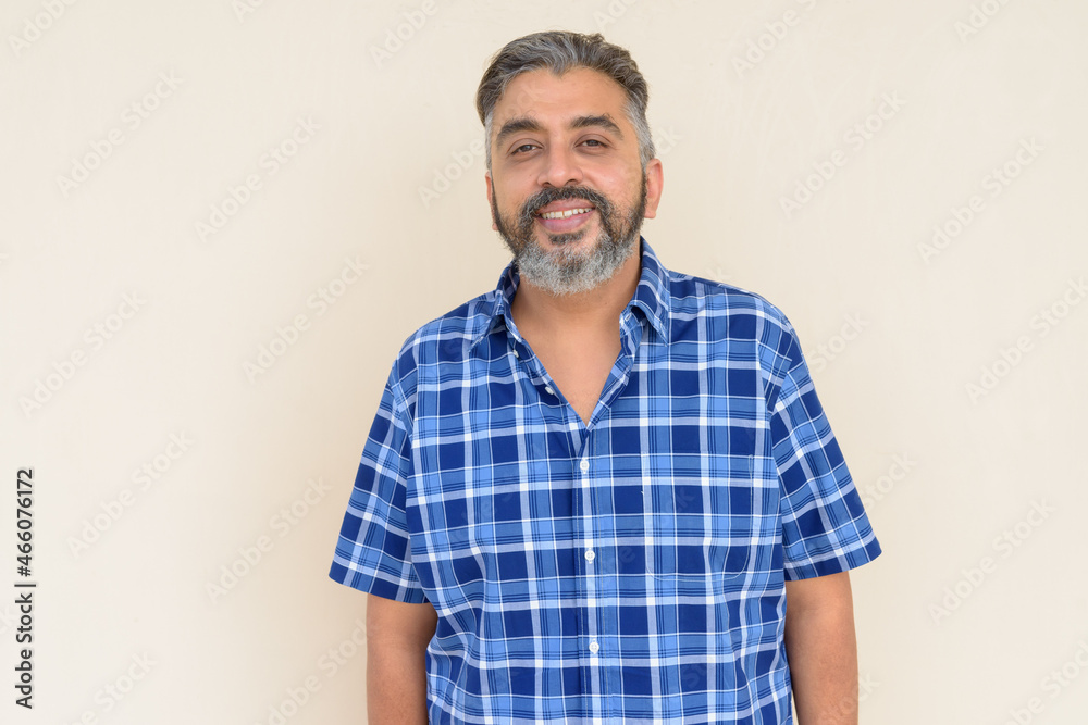 Portrait of bearded Indian businessman smiling against plain background Portrait of bearded Indian businessman smiling against plain background
