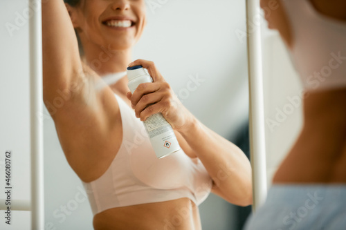 Foto Close-up of happy woman uses deodorant spray on her underarm at home